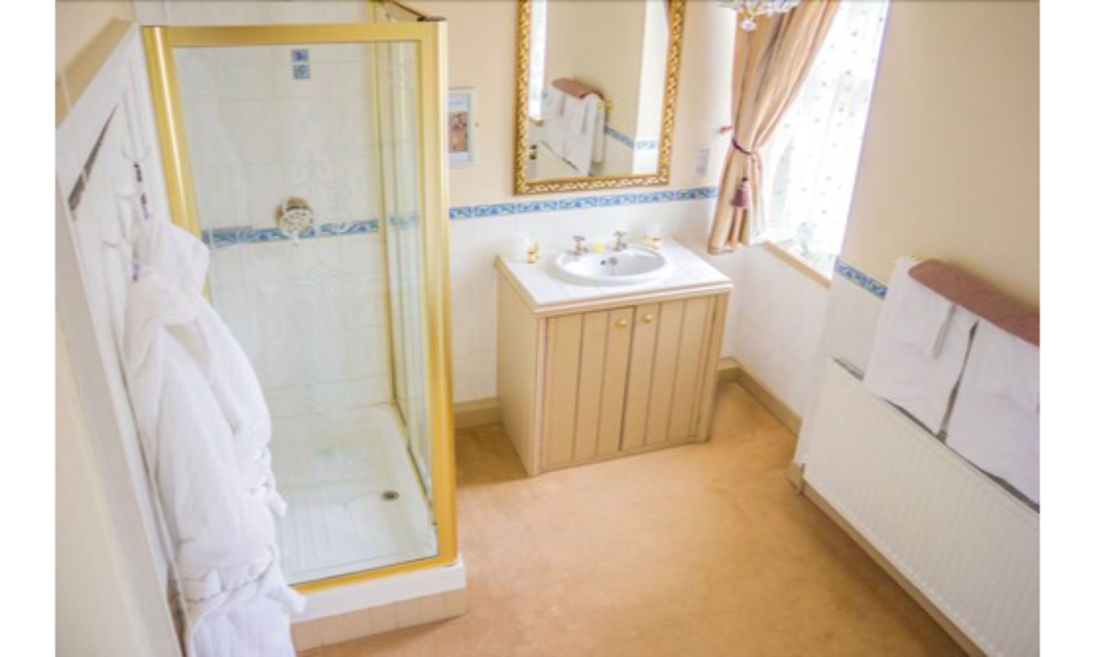 A bathroom with a glass shower enclosure, a sink with a mirror above it, and a towel hanging on the wall.