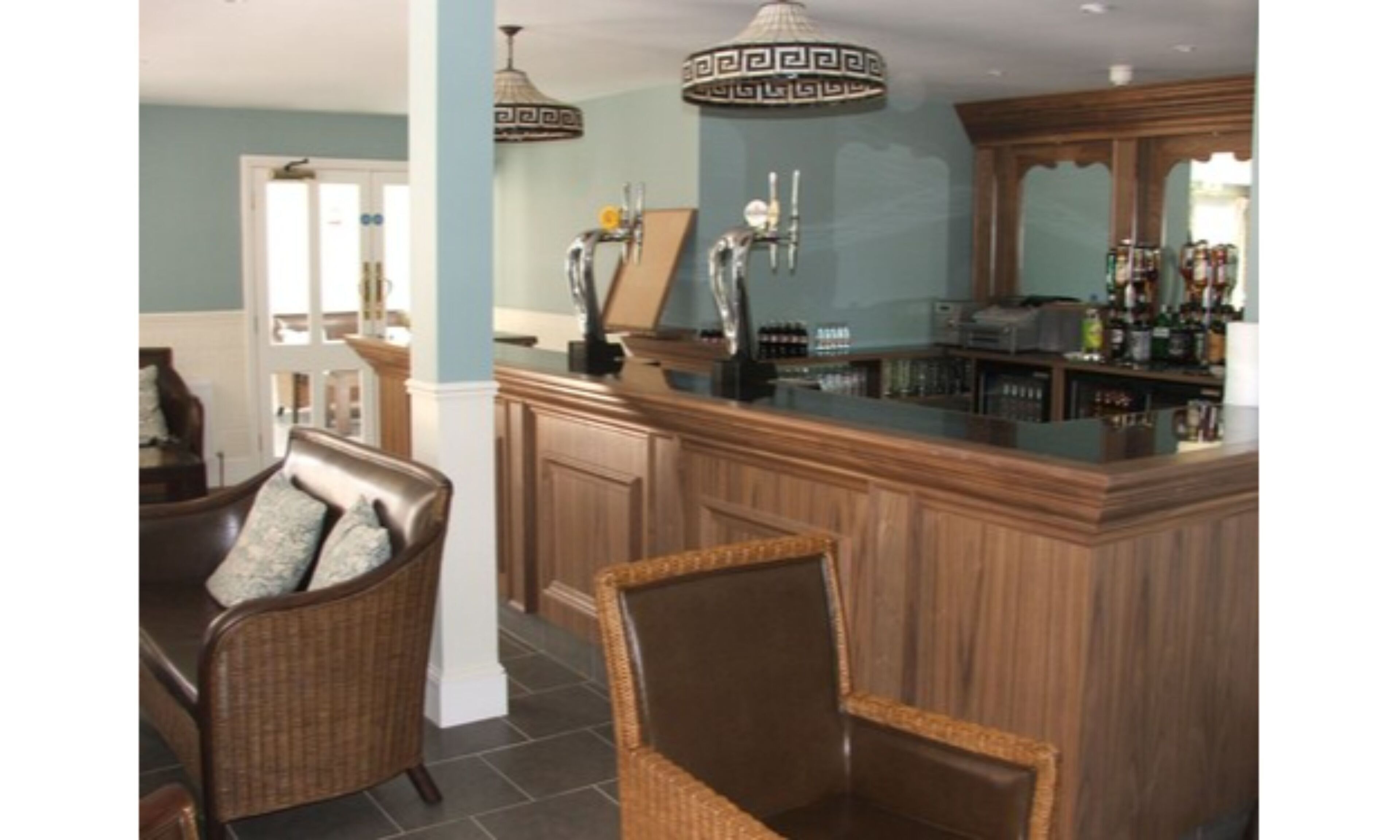 A bar area with wooden cabinets, wicker chairs, and a bar counter.
