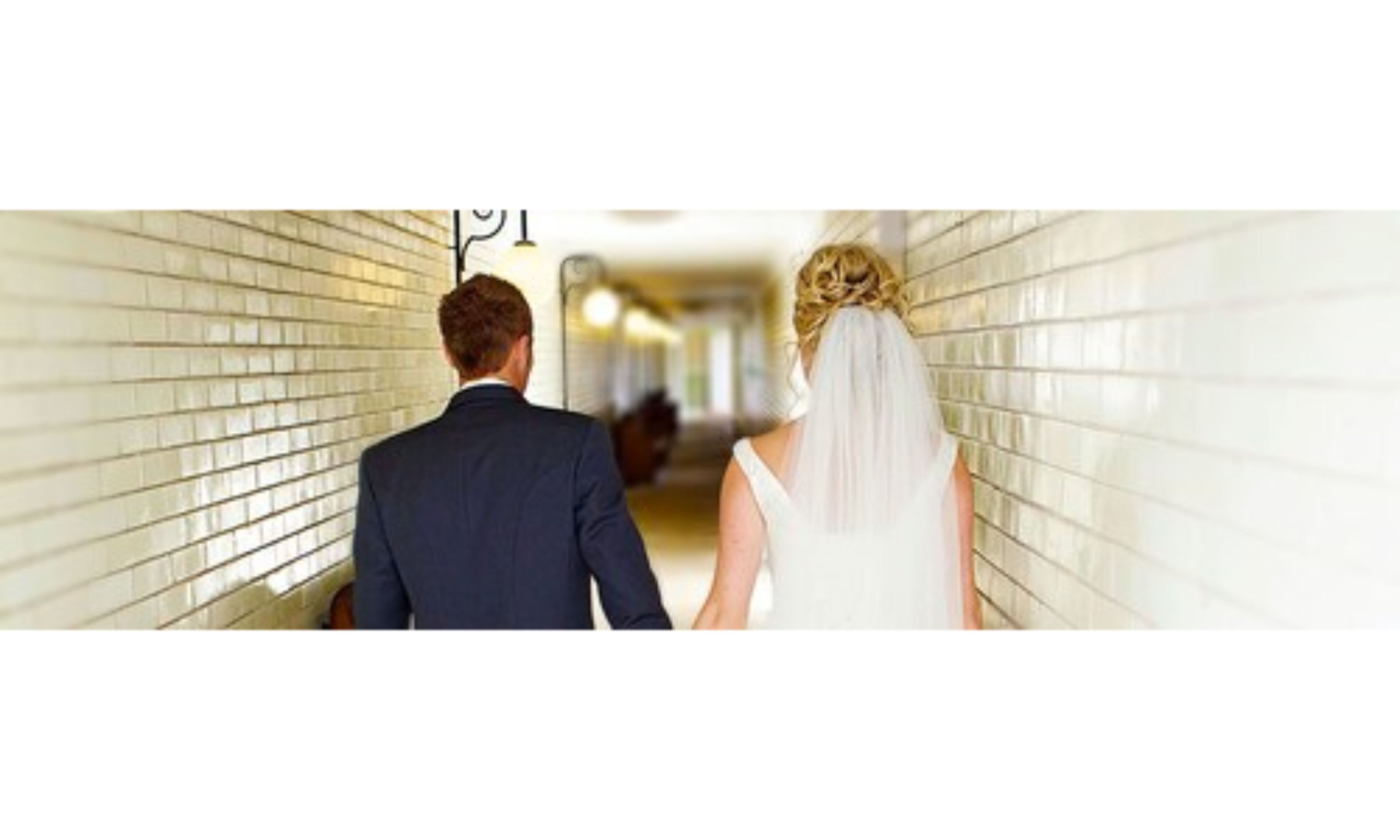 A couple walking down a hallway with tiled walls.