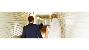 A couple walking down a hallway with tiled walls.