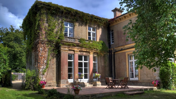 A historic building with a garden patio, large windows, and a stone facade. - Albert Cottage Hotel (East Cowes)