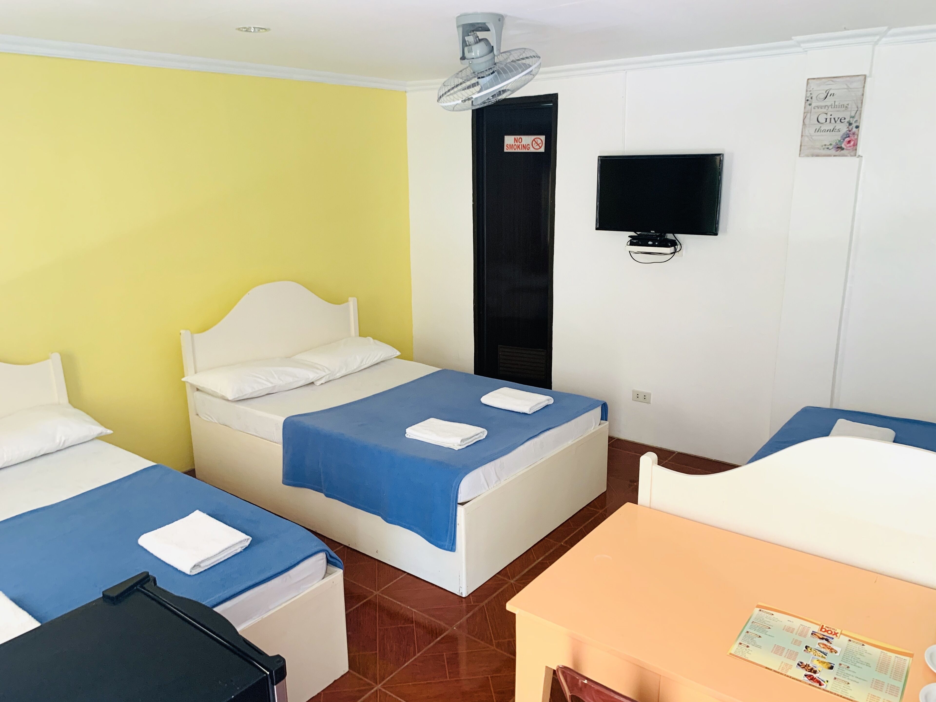 Habitación de hotel con dos camas, un escritorio, una silla, un televisor y un letrero de no fumar.