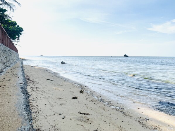 Una playa con un muro de piedra y agua tranquila.
