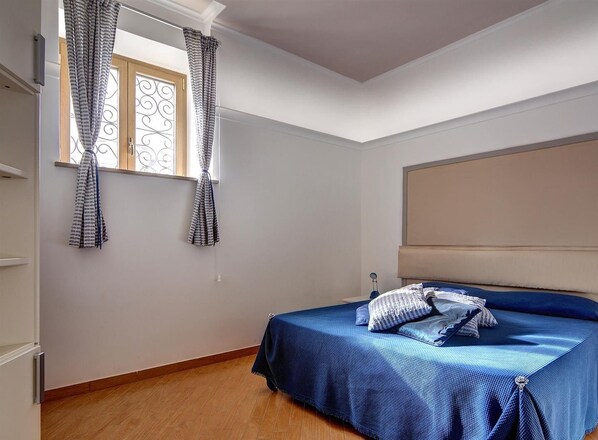 A bedroom with a bed, a window with curtains, a radiator, and a headboard. - Casa dell'Accademia (Sorrento)
