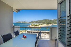 Un balcone con tavolo e sedie, vista sulla spiaggia e sull'oceano.