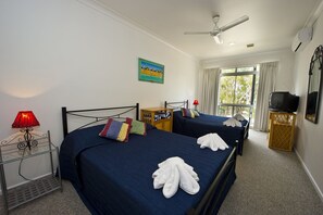 A hotel room with two beds, a ceiling fan, a TV, and a window with curtains. - Beachcomber Unit 2 (Arcadia)