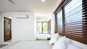 Een moderne hotelkamer met een groot bed, een raam met zonwering, een airconditioning en een deur.