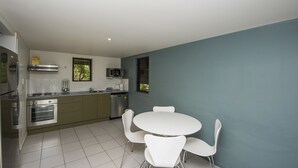 Una cocina moderna con comedor, que incluye electrodomésticos de acero inoxidable, armarios blancos y una pared de acento color aguamarina.