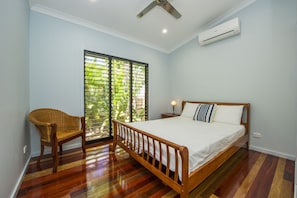A bedroom with a wooden bed, a chair, a nightstand, and a ceiling fan.