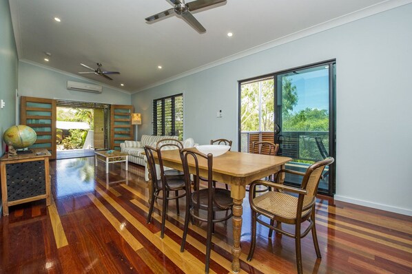 A spacious room with a wooden dining table, chairs, a globe on a side table, and a ceiling fan.