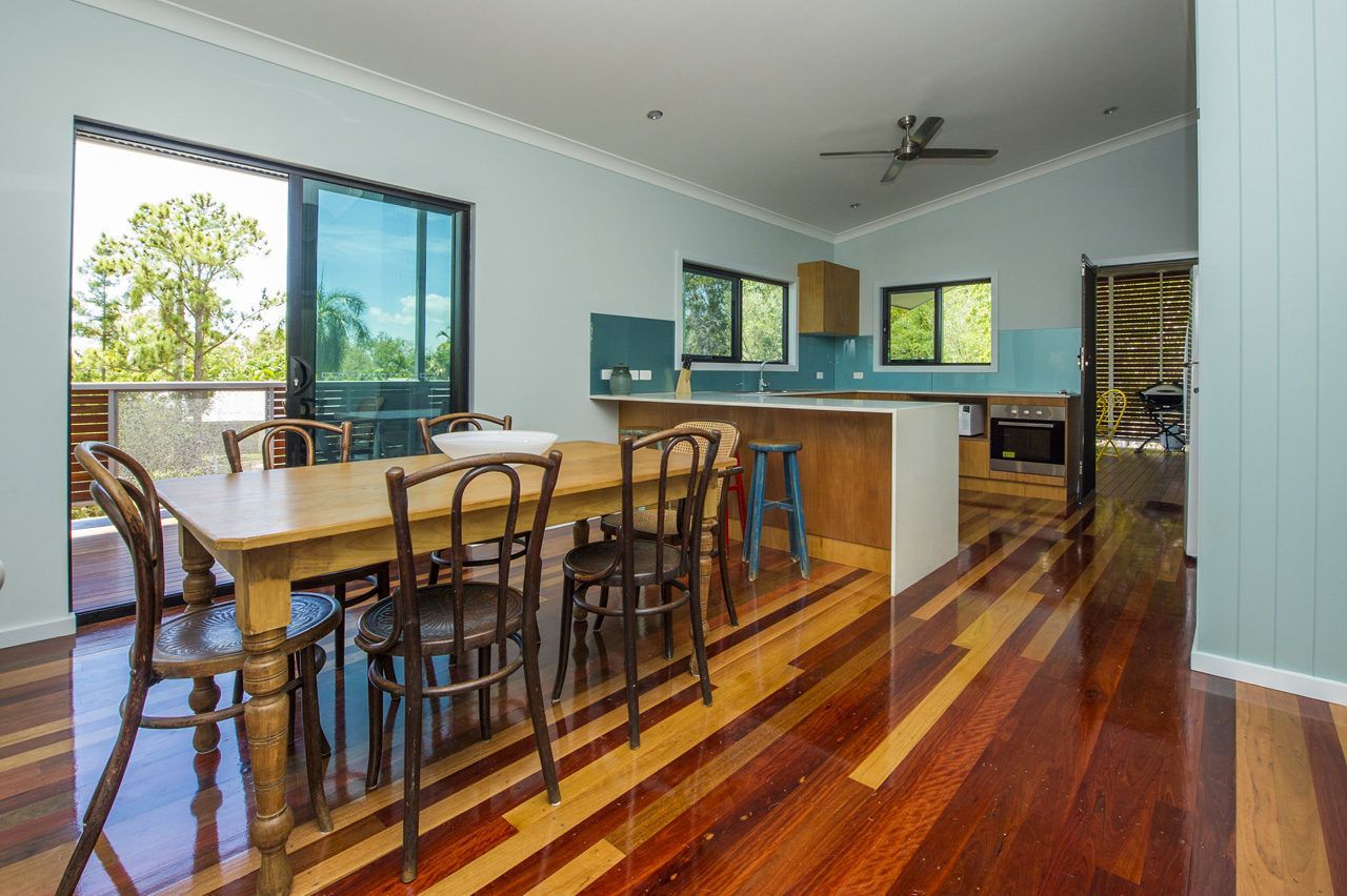 Une cuisine moderne avec une table et des chaises en bois, de grandes fenêtres et une vue sur l’extérieur.