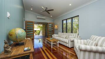 A living room with striped sofas, a wooden coffee table, a globe, and a ceiling fan.