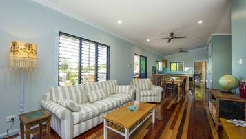 A spacious living room with striped sofas, a wooden coffee table, and a dining area with chairs and a table.