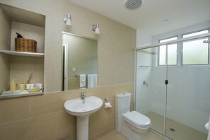 A bathroom with a sink, toilet, and glass shower enclosure.
