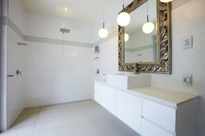 A modern bathroom with a large mirror, white vanity, and a shower area. - Essence Beachfront Retreat (Horseshoe Bay)