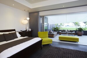 A modern bedroom with a large bed, a yellow armchair, and a sofa set. - Essence Beachfront Retreat (Horseshoe Bay)