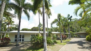 A building with a simple, single-story structure, surrounded by palm trees and greenery. - John's Tropical Island Home (Nelly Bay)