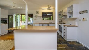Cocina moderna con una isla central, armarios blancos y vistas a un espacio exterior cubierto.