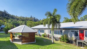 A campsite with a wooden pavilion and two mobile homes with red doors. - Kooyong Apartment 3 (Arcadia)