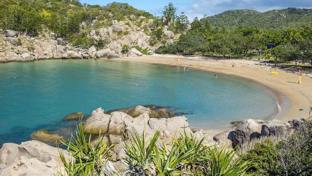 Un paysage côtier avec une mer bleue et limpide, une côte rocheuse et une plage de sable.