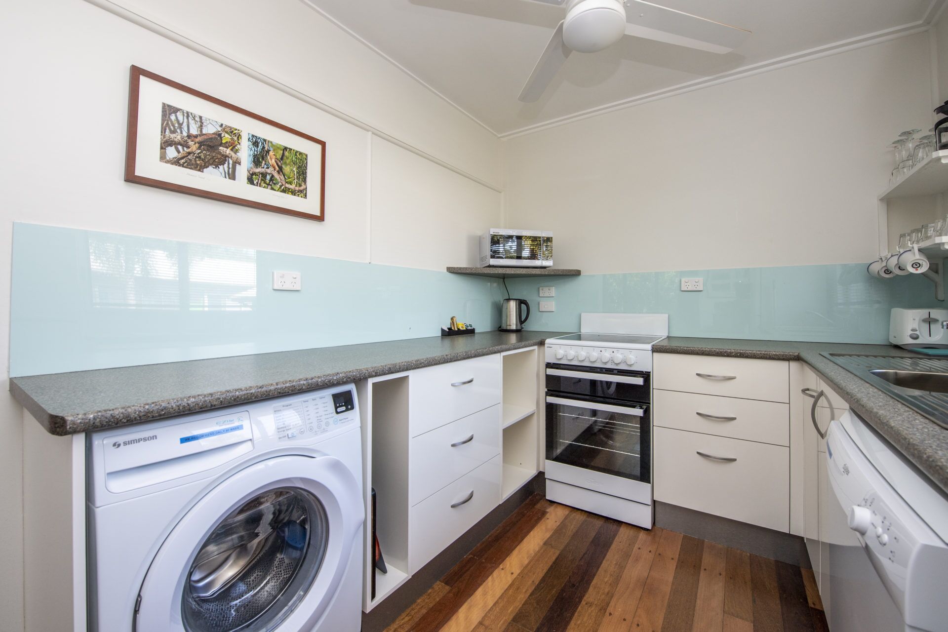A compact kitchen with a washing machine, oven, microwave, and a small countertop.
