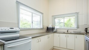 Una cocina moderna con armarios blancos, estufa, microondas y pileta.