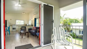 Un espacio habitable compacto con kitchenette, zona de comedor y balcón con una silla.