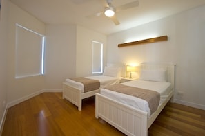 A bedroom with two single beds, a ceiling fan, and a radiator.