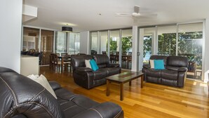 Ein geräumiges Wohnzimmer mit Ledersofas, einem Holztisch und einem Essbereich mit Stühlen und Tisch.