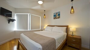 Ein Schlafzimmer mit Bett, Nachttisch, Lampe und einem Kunstwerk an der Wand.