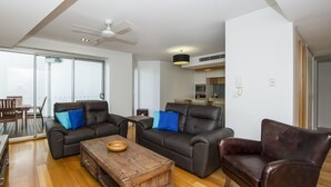 Una sala de estar moderna con dos sofás, una mesa de centro y una zona de comedor con mesa y sillas.