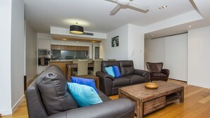 Una sala de estar moderna con sofás de cuero, una mesa de centro de madera y un comedor al fondo.