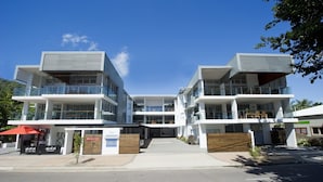 A modern multi-story building with balconies, a covered entrance, and a clear sky. - Maggies Beachfront Apt. 7 (Horseshoe Bay)