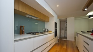 A modern kitchen with white cabinetry, a wooden countertop, and a visible stove. - Maggies Beachfront Apt. 7 (Horseshoe Bay)