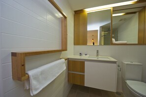 A bathroom with a wooden vanity, a white toilet, and a mirror above the sink.
