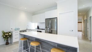 Una cocina moderna con armarios blancos, un refrigerador de acero inoxidable y una isla grande con taburetes de bar.