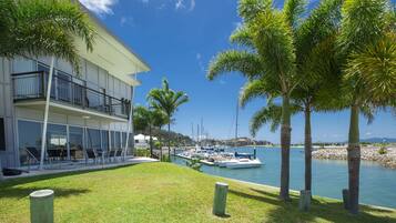A modern building with a balcony overlooking a marina with boats.
