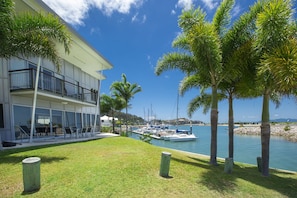 A modern building with a balcony overlooking a marina with boats.