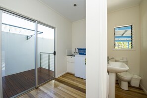 Eine kompakte Küche mit integriertem Waschtrockner, einer kleinen Spüle und einem Fenster mit Jalousien.