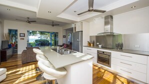 Une cuisine moderne dotée d’un îlot central, d’appareils électroménagers en acier inoxydable et d’un ventilateur de plafond.