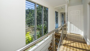 Un intérieur moderne avec de grandes fenêtres, un escalier en bois et une porte blanche.