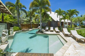 A swimming pool with lounge chairs and palm trees.