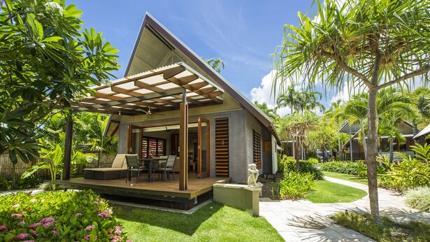 A modern house with a covered patio, a lawn, and tropical plants. - Pure Magnetic Villa 1 (Nelly Bay)