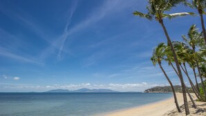 A beach with clear skies, calm water, and palm trees. - Pure Magnetic Villa 1 (Nelly Bay)