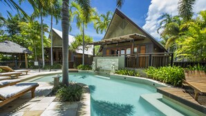 A resort with a swimming pool, lounge chairs, and tropical landscaping. - Pure Magnetic Villa 1 (Nelly Bay)