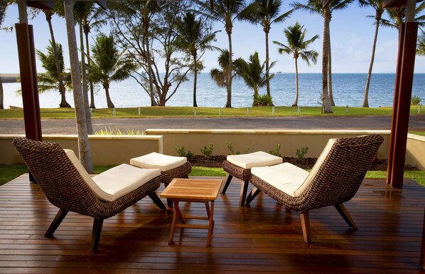 A wooden deck with wicker furniture and a view of the ocean.