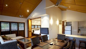 A modern kitchen with a built-in refrigerator, a dining area with a large table and chairs, and a cozy living room with a sofa and a television.
