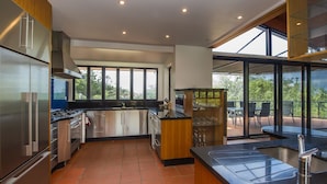 Une cuisine moderne dotée d’appareils électroménagers en acier inoxydable, d’une grande fenêtre et d’un balcon avec coin salon extérieur.