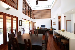 Amplia sala de estar con una gran mesa de comedor, diversas opciones de asientos, televisor y una zona de cocina.