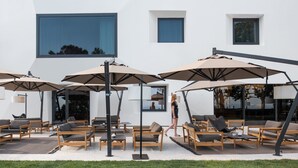 An outdoor seating area with multiple tables and chairs, large umbrellas, and a modern building in the background. - Briig Boutique Hotel (Split)